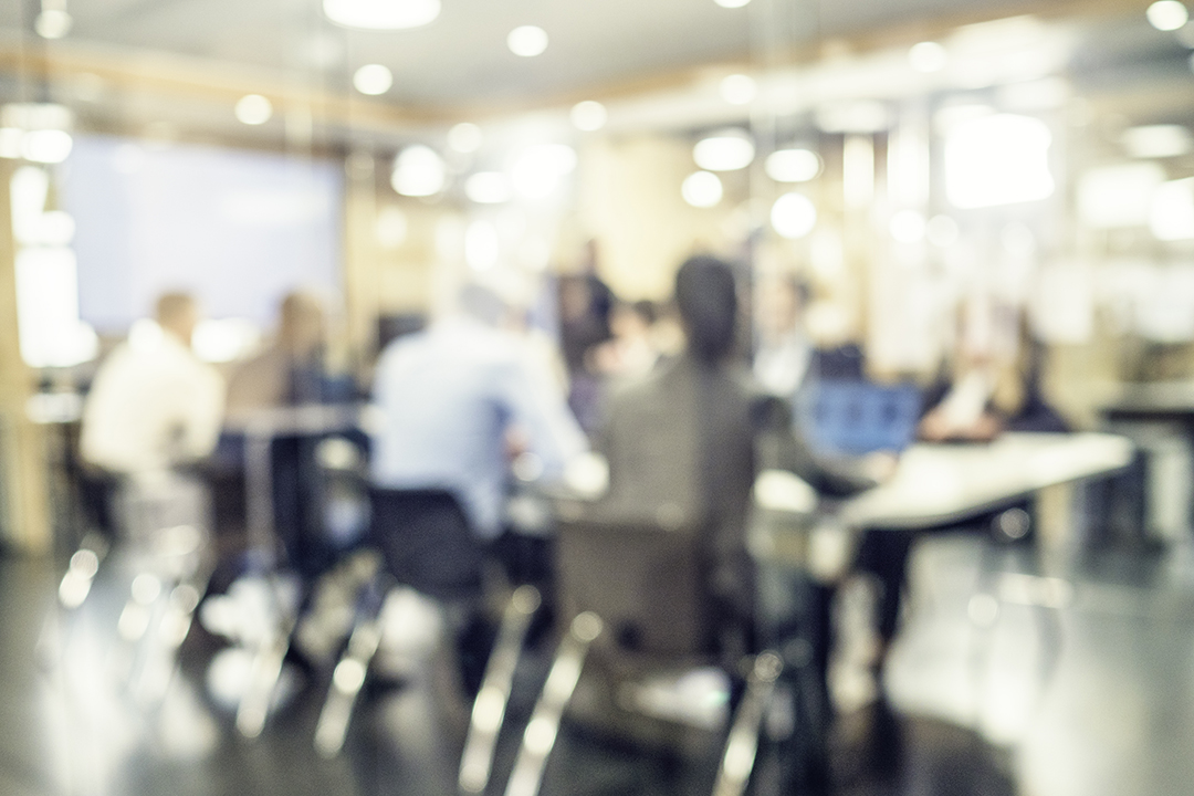 Out of focus shot of a group of people seated around a conference table.