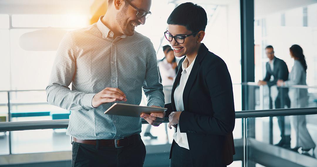 Two people working together over a tablet.