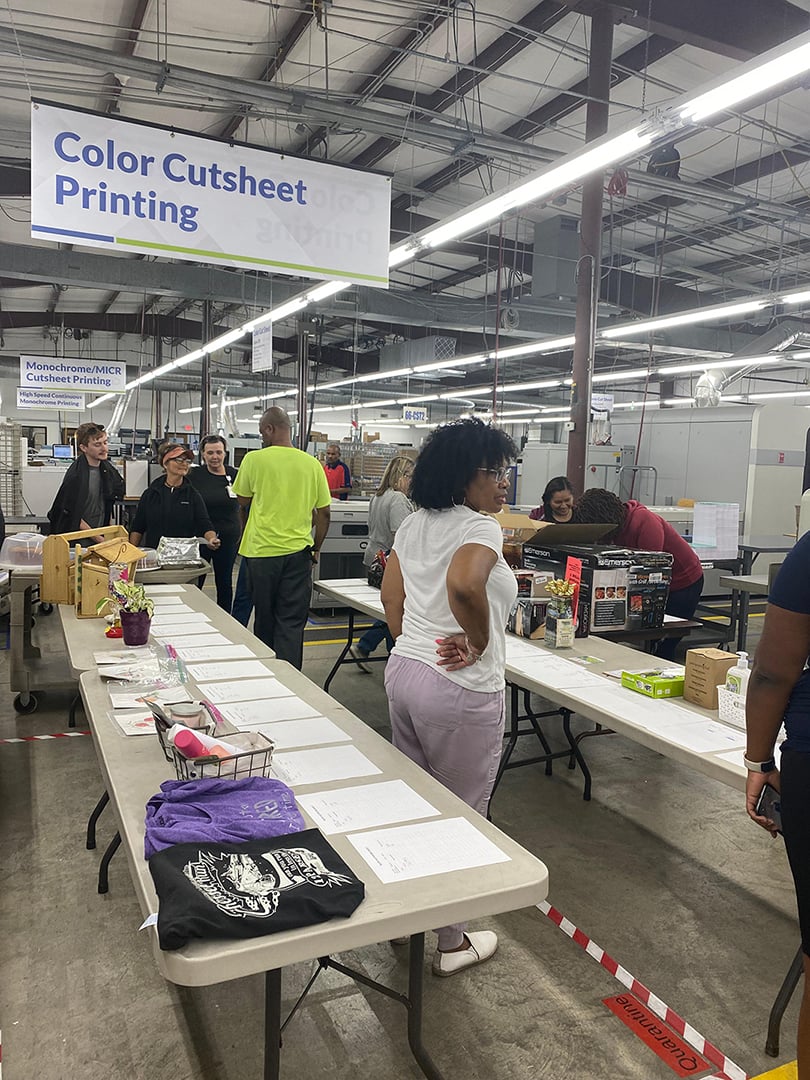 Monroe facility employees browse the items donated for silent auction between tables set up in the warehouse 